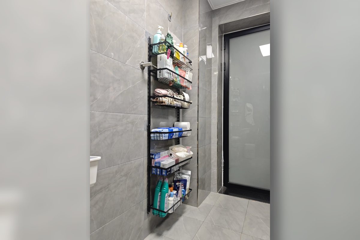 Narrow bathroom shelf beside a doorway holding toiletries in a compact apartment bathroom.