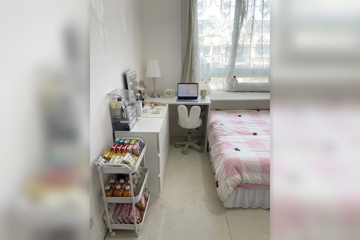 Small apartment bedroom with a rolling cart and compact desk storage.