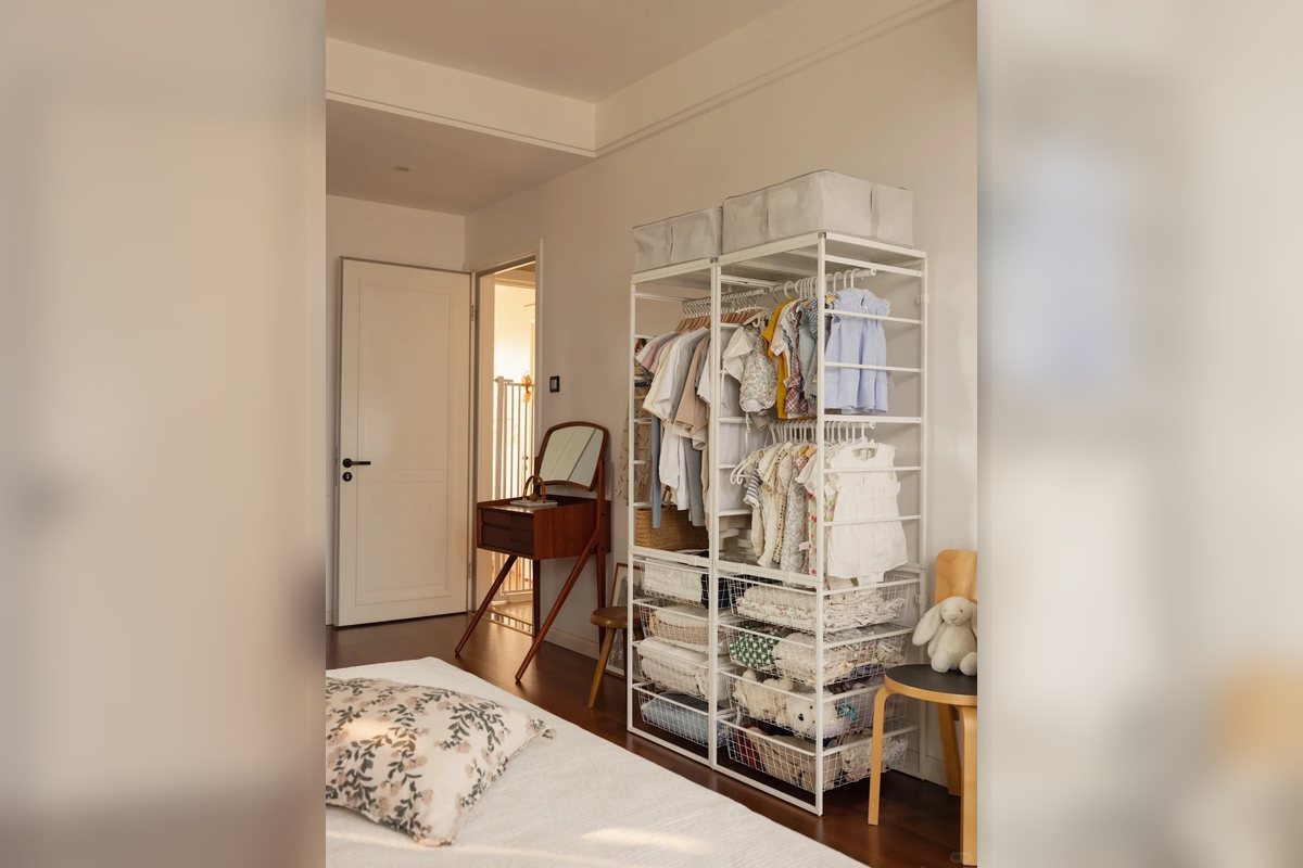 Open garment rack with shelves and folded storage in a small bedroom.