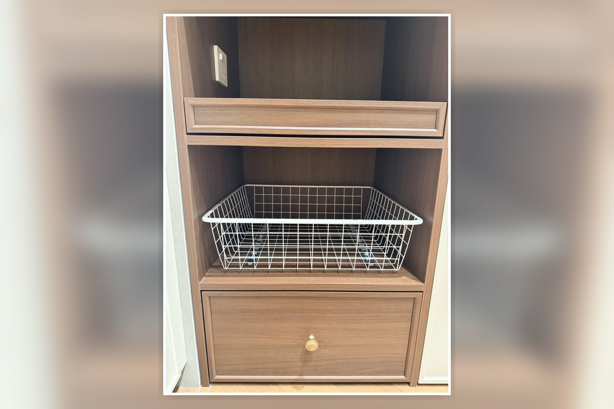 Wire pull-out basket installed inside a compact apartment kitchen cabinet.